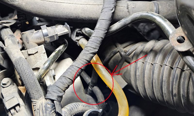 Image of an engine with a highlighted four-way connector in hoses.