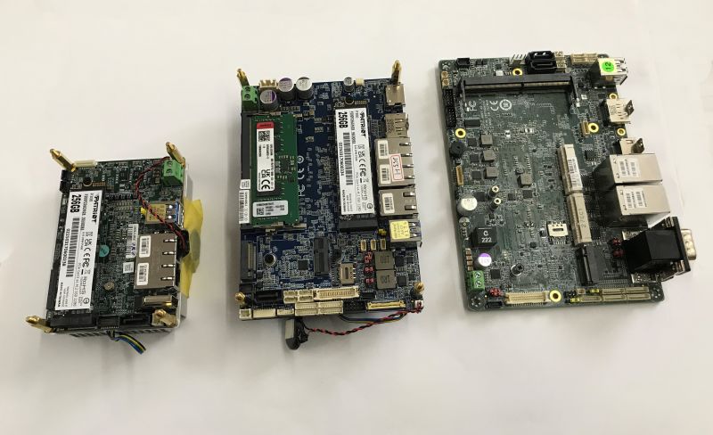 Trzy płytki elektroniczne z modułami pamięci i portami USB/Ethernet na białym tle
