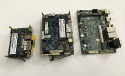Trzy płytki elektroniczne z modułami pamięci i portami USB/Ethernet na białym tle