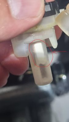 Zbliżenie na plastikowy element w zmywarce z zaznaczoną białą częścią.