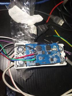 Blue PCB in a white casing with soldered wires and a strip of clear tape on top