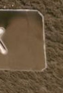 Close-up of metal plate corner with rounded edges on brown textured surface