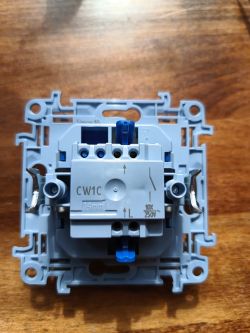 Mechanizm włącznika światła CW1C z niebieskimi elementami na drewnianym blacie