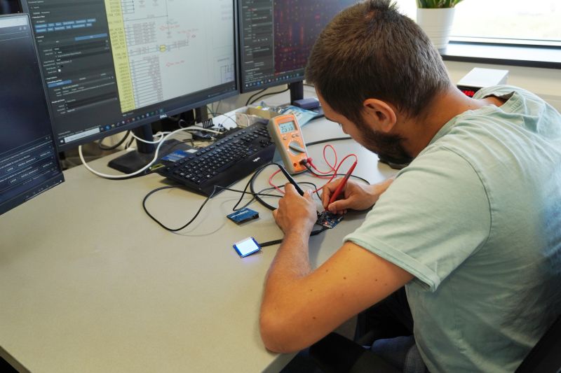 Man testing a circuit board using a multimeter and soldering tool