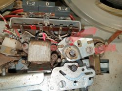 Zbliżenie wnętrza magnetofonu z widocznymi kablami i elementami mechanicznymi.