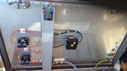 Wnętrze metalowej szafy elektrycznej z widocznymi elementami okablowania i przełącznikami.