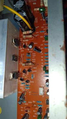 Widok wnętrza wzmacniacza z układem elektronicznym i widocznymi elementami takimi jak tranzystory, rezystory i kondensatory.