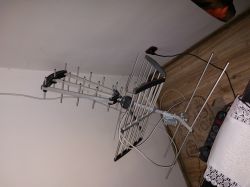 Metalowa antena kierunkowa TV leży na podłodze obok kabla i listwy zasilającej.