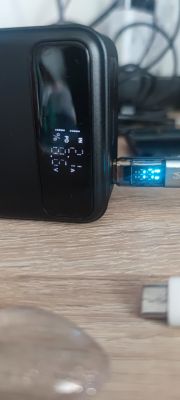 Zbliżenie na powerbank z podłączonym kablem USB-C z wyświetlaczem pokazującym parametry ładowania.