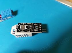 Module with three pins on a blue mat, next to a DHT11 sensor.