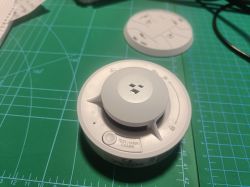 Tuya smoke detector with PCB labeled v2 on a green cutting mat.
