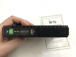 Front of a black IPS mini UPS with power button, 9/12 V indicators and a USB port, held in a hand