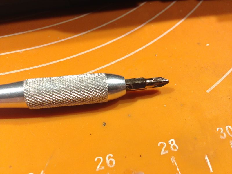 Metalowy uchwyt z wymiennym bitem na pomarańczowym tle.