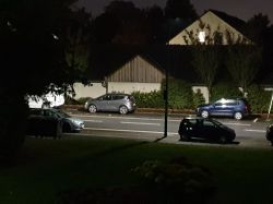 Ulica nocą oświetlona jasną latarnią LED, zaparkowane samochody przy krawężniku
