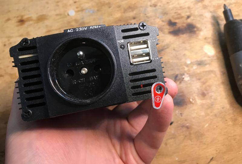 Przednia część czarnej przetwornicy samochodowej z gniazdem 230V i portami USB