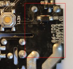 A section of a circuit board with visible traces, electronic components, and a black solder mask.