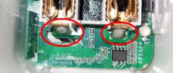 Damaged PCB with two swollen capacitors marked in red