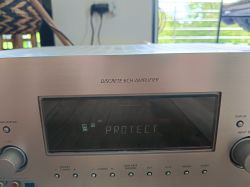Panel przedni amplitunera z napisem „PROTECT” na wyświetlaczu i „DISCRETE 6CH AMPLIFIER” nad nim