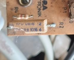 Zbliżenie na komponent elektroniczny na płytce drukowanej z widocznymi oznaczeniami.