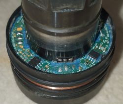 Zbliżenie na wnętrze elementu elektronicznego z widoczną płytką drukowaną.