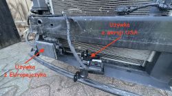 Widok przedniej części samochodu Hyundai Tucson z wymontowanym zderzakiem, pokazujący dwa radary AEB: jeden z wersji europejskiej, drugi z USA, oznaczone czerwonymi napisami.