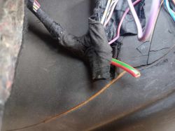 Zbliżenie na wiązkę przewodów samochodowych owiniętą czarną taśmą izolacyjną z widocznym czerwono-zielonym przewodem.