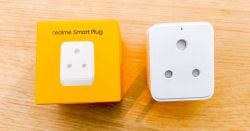 Realme Smart Switch with Packaging A white Realme smart switch next to an orange box labeled realme Smart Plug.