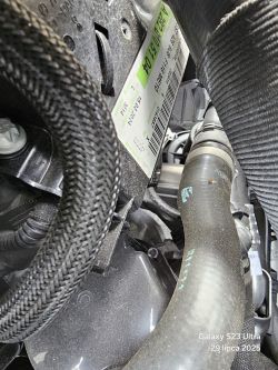 Zbliżenie na komorę silnika z widoczną etykietą części i przewodami