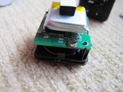 Interior of a Disassembled Electronic Device Disassembled electronic device with a visible battery and circuit board on a carpet.