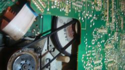 Wnętrze urządzenia elektronicznego z widoczną płytką drukowaną i mechanizmem z paskiem