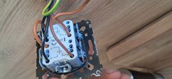 Close-up of a light switch mechanism wiring with brown, black, and yellow-green wires on a metal frame