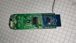 Close-up of a circuit board with a blue module and wiring on graph paper background.