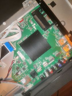 Zdjęcie wnętrza telewizora Sharp Aquos z widoczną płytą główną i przewodami.