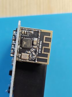 Wireless module labeled TX-803 V2.0 with control chip and PCB antenna on blue surface