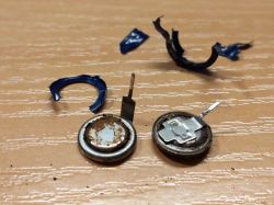 Zużyte baterie guzikowe i części obudowy na stole.