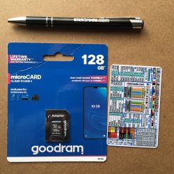 Pen, Goodram microSD 128 GB memory card, and color chart card on a brown table background.