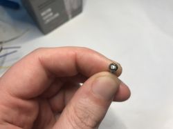 Torx screw held between fingers against light background