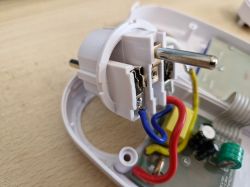 Wnętrze rozebranego gniazdka elektrycznego z widocznymi przewodami.