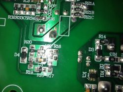 Zdjęcie zielonej płytki drukowanej (PCB) z widocznymi elementami elektronicznymi i oznaczeniami.