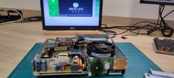 Wnętrze konsoli Xbox 360 Slim z otwartą pokrywą i wyświetlonym ekranem Xbox Live w tle.