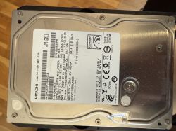 Twardy dysk marki Hitachi o pojemności 750 GB leżący na powierzchni drewnianej.