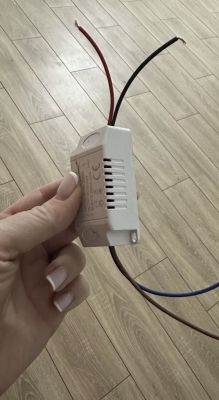 Zasilacz LED trzymany w dłoni z podłączonymi czterema kolorowymi przewodami
