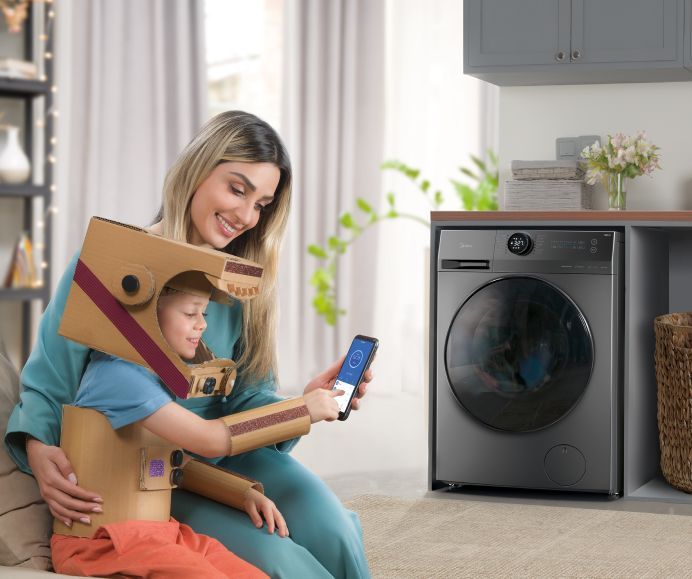 Zdalne sterowanie pralką Midea Kobieta i dziecko w kartonowym stroju sterują pralką Midea smartfonem.