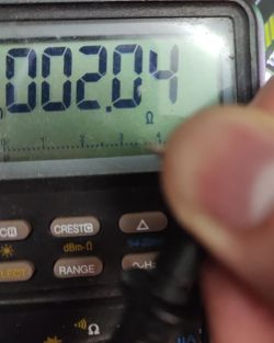 Multimeter display showing a resistance value of 2.04 ohms, partially obscured by a finger.