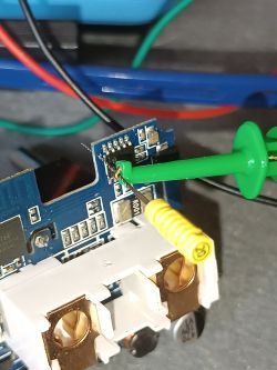 Close-up of a measurement probe connected to a circuit board with electronic components and wires.