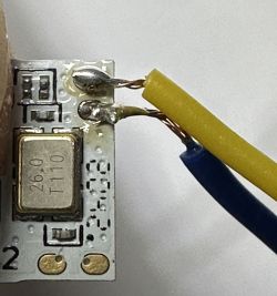 Close-up of a circuit board with attached yellow and blue wires.