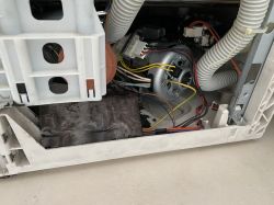 Widok wnętrza zmywarki z widocznymi kablami i elementami mechanicznymi.