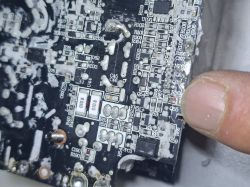 Zbliżenie płytki PCB z elementami SMD, oznaczeniami (R, C, Q, VR) i palcem wskazującym obszar