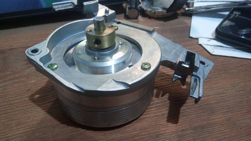 Element mechaniczny z metalową obudową i wałem na drewnianym blacie