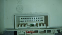 Zbliżenie na biały złącze elektryczne z widocznymi pinami w module samochodowym